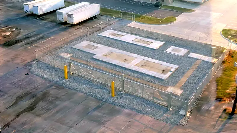 Rendered view of the graded rock pad and perimeter fence, equipment pads poured, nothing installed yet.