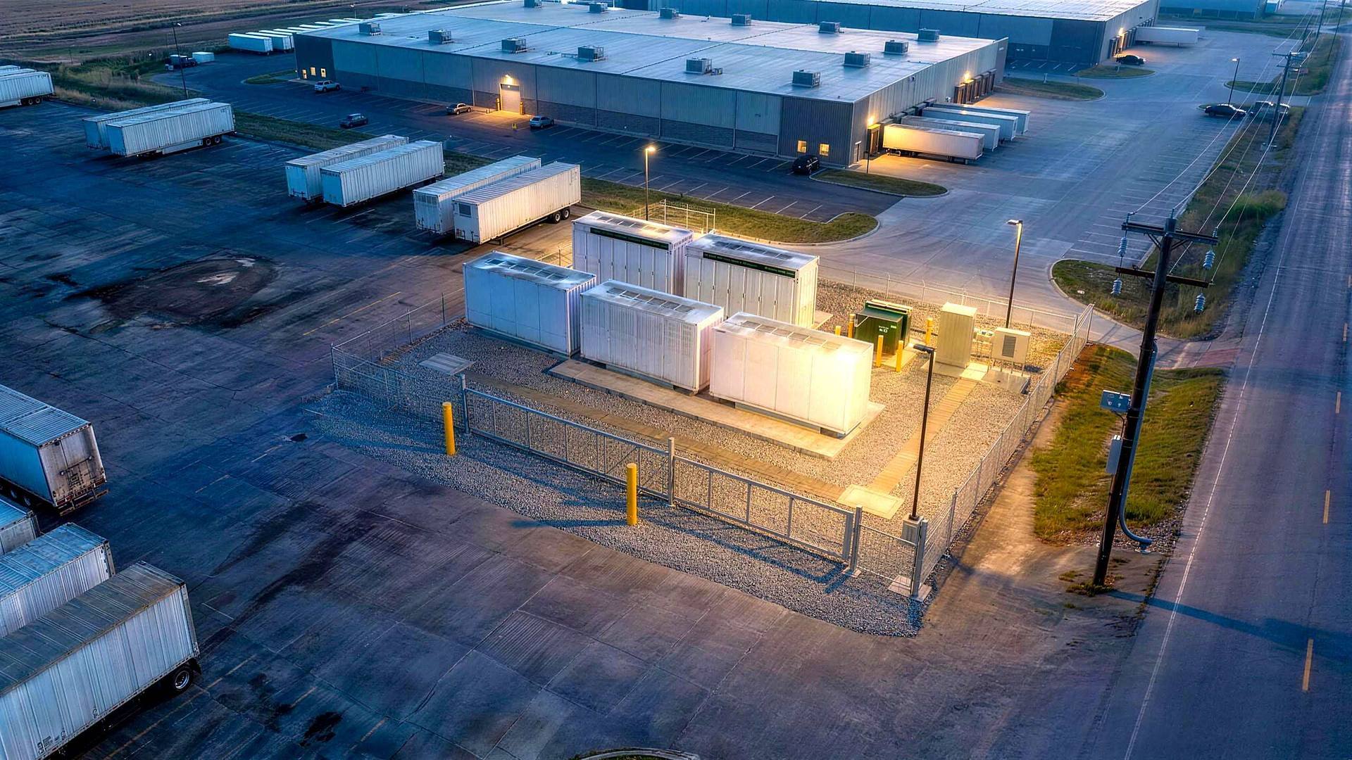 Rendered dusk view of the whole yard: trailer rows dark on the apron, the fenced storage pad task-lit in the far corner.