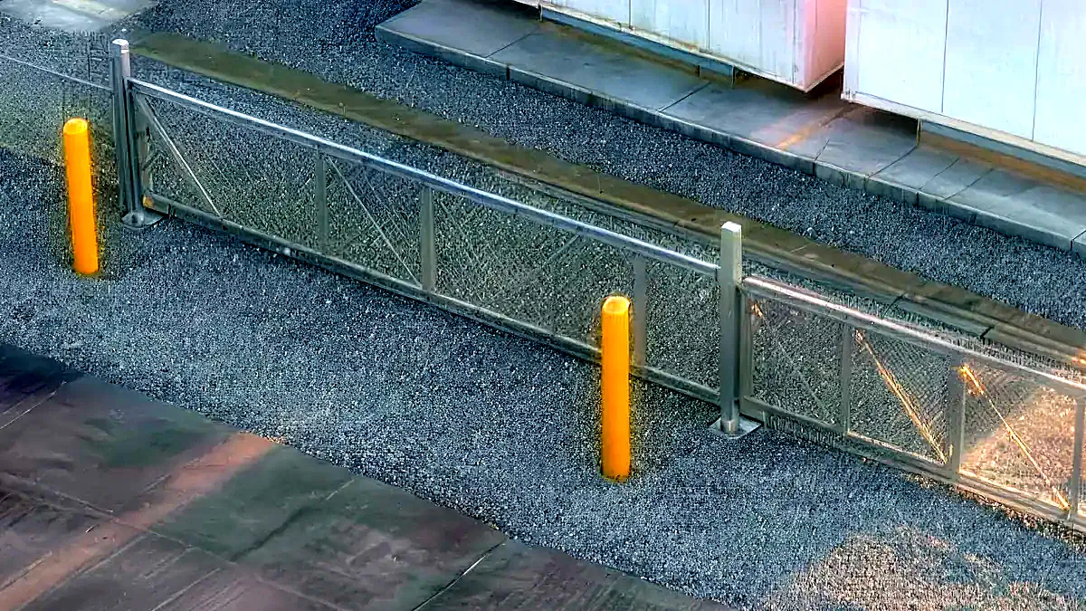 Rendered detail of the chain-link perimeter fence, battery enclosures beyond.